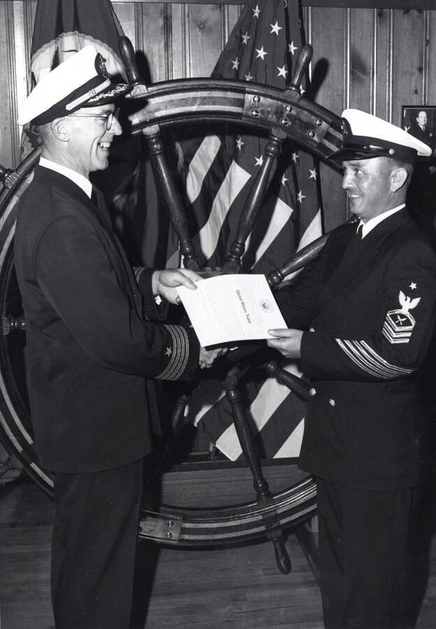 1962 photograph of Naval Science. Captain Davey congratulating Robert Miller. Donor: Publications Dept. [PG1_209-13]