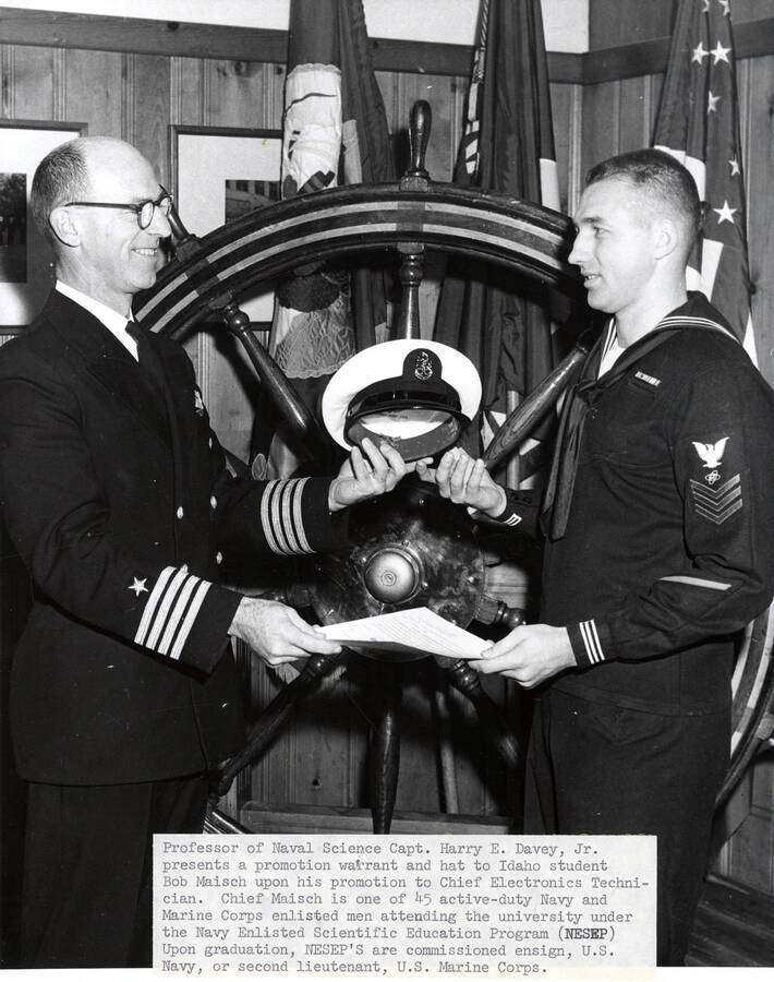 Naval Science. University of Idaho. Capt. Harry E. Davey presents promotion warrant and hat to student Bob Maisch. [209-6]