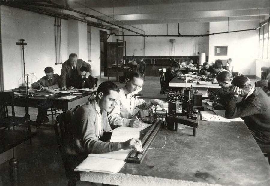 1933 photograph of Physics building. Students work with equipment at lab workstations. [PG1_213_01]