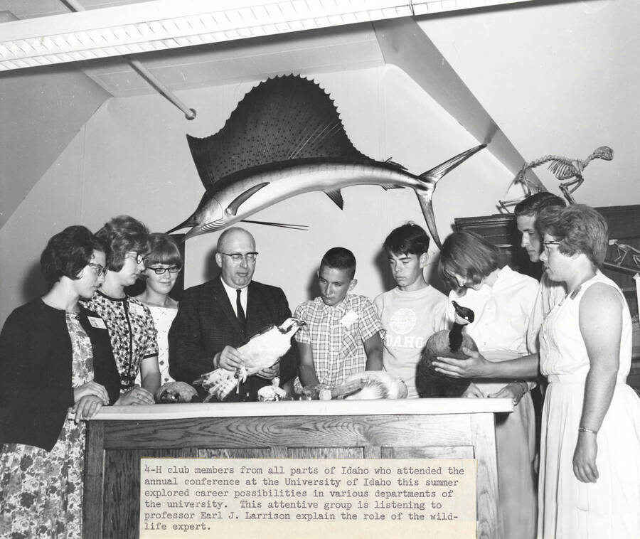 1965 photograph of Zoology building. Professor works with 4-H members explaining the role of wildlife expert. [PG1_214_18]
