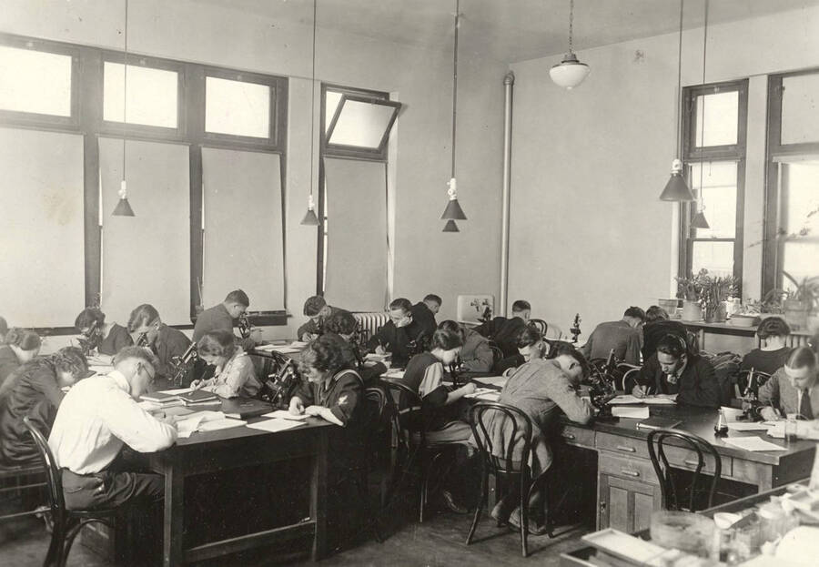 1936 photograph of Botany building. Students work with microscopes in the lab. [PG1_215_03]