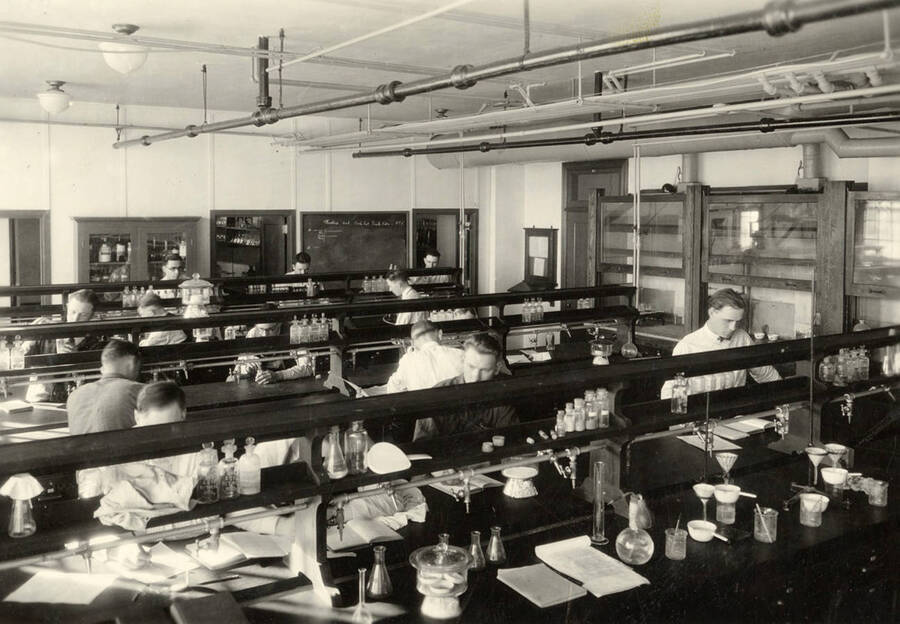 1928 photograph of Agricultural chemistry building. Students work with equipment at lab workstations. [PG1_216_01]