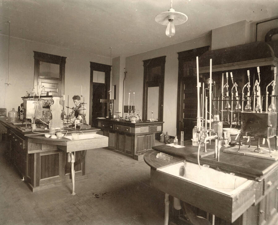 1906 photograph of Agricultural chemistry building. Students work with equipment at lab workstations. [PG1_216_06]