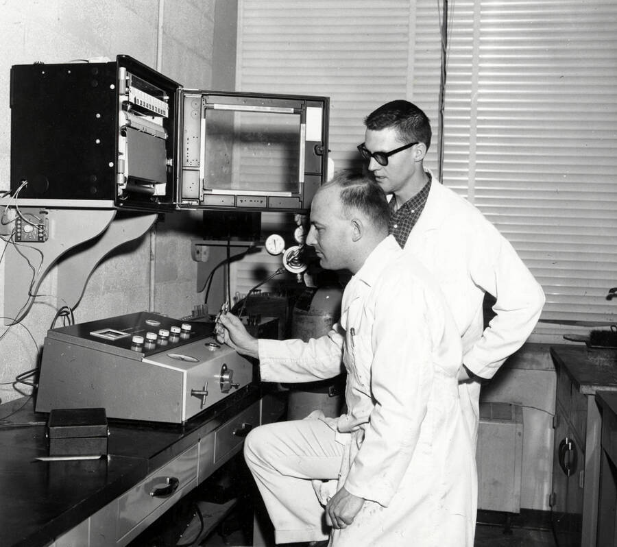1961 photograph of Agricultural chemistry building. Professor and student work with equipment. [PG1_216_11]