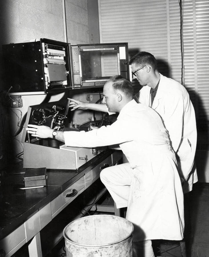 1961 photograph of Agricultural chemistry building. Professor and student work with equipment. [PG1_216_12]