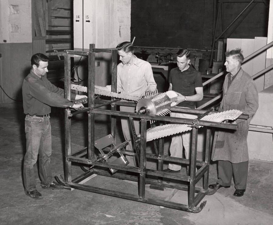 1953 photograph of Agricultural engineering building. Professor demonstrates the equipment to students in the shop. [PG1_217_10]