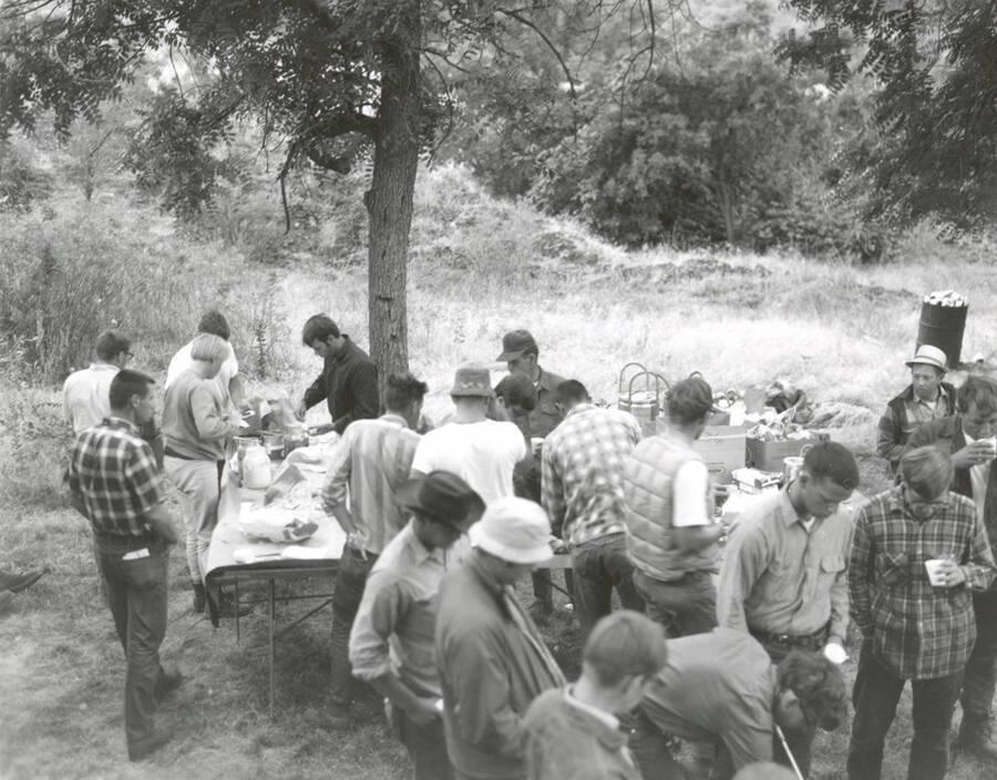 1969 photograph of College of Forestry. Students gather around tables at the campsite during the forestry summer camp. Also print. Donor: Fred Johnson. [PG1_218-71e]