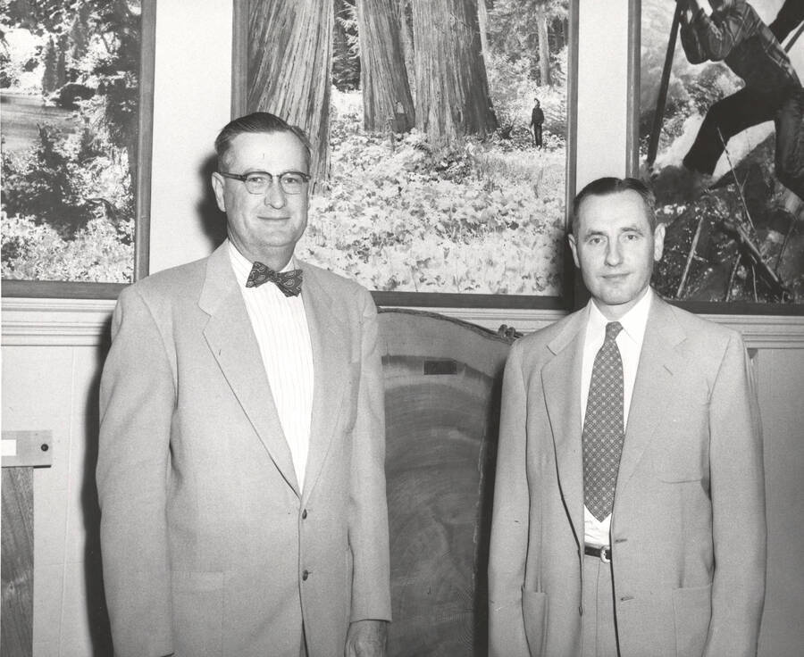 1953 photograph of College of Forestry. President Buchanan with the new Forestry Dean Ernest Wohletz stand in front of photographs of forestry scenes. [PG1_218-20]