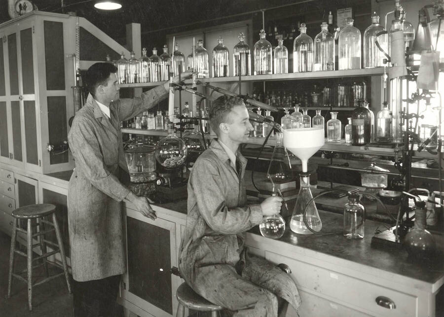 1936 photograph of College of Forestry. McCarthy and Larsen work at lab tables in the wood conversion laboratory. Donor: Publications Dept. [PG1_218-29]