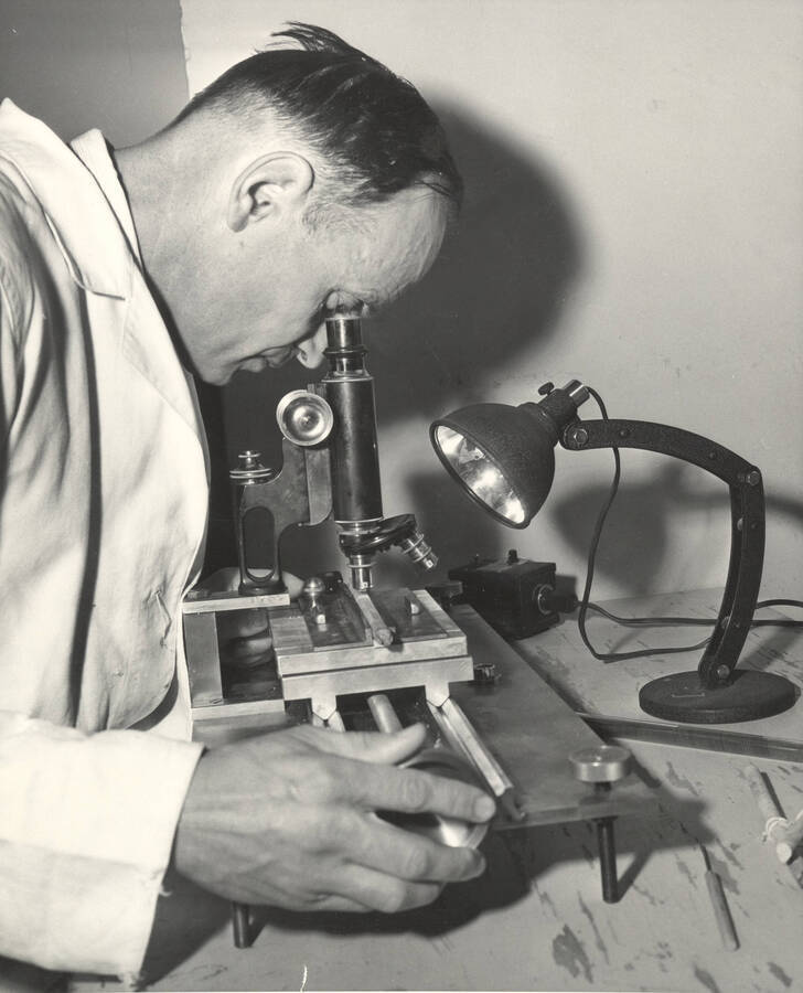 1963 photograph of College of Forestry. John P. Howe, professor of wood utilization, operates a microscope. Donor: Publications Dept. [PG1_218-31]