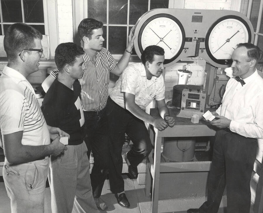 1960 photograph of College of Forestry. John Howe, professor of wood utilization, with four students at a wood compression machine. Donor: Publications Dept. [PG1_218-38]