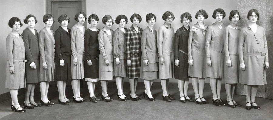 1928 photograph of Home Economics. Seniors line up to show the dresses made in their class. [PG1_221-011]