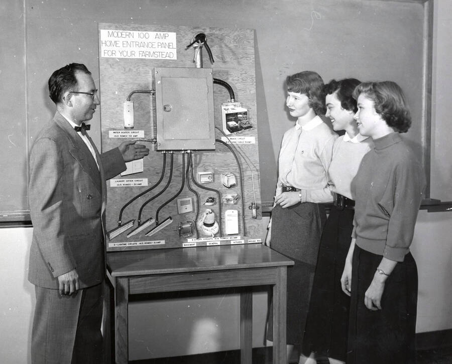 1955 photograph of Home Economics. William H. Knight demonstrates electrification to Patricia Stewart, Clara Armstong and Elaine Hyland. Donor: Publications Dept. [PG1_221-047]