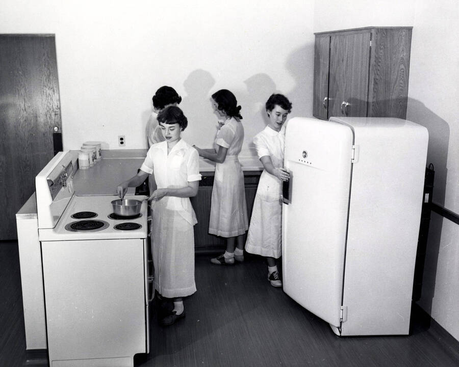 1955 photograph of Home Economics. Jan Morgan, Barbara Pierce, and two unidentified students work in a kitchen laboratory. Donor: Publications Dept. [PG1_221-054]