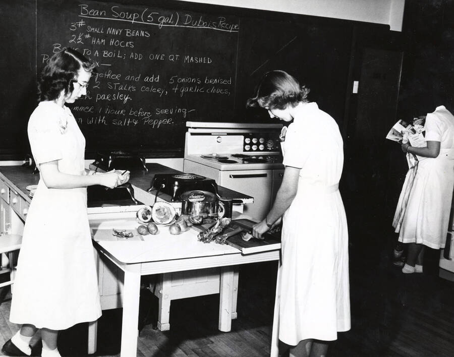 1955 photograph of Home Economics. Students cooking bean soup in a kitchen classroom. Donor: Publications Dept. [PG1_221-056]