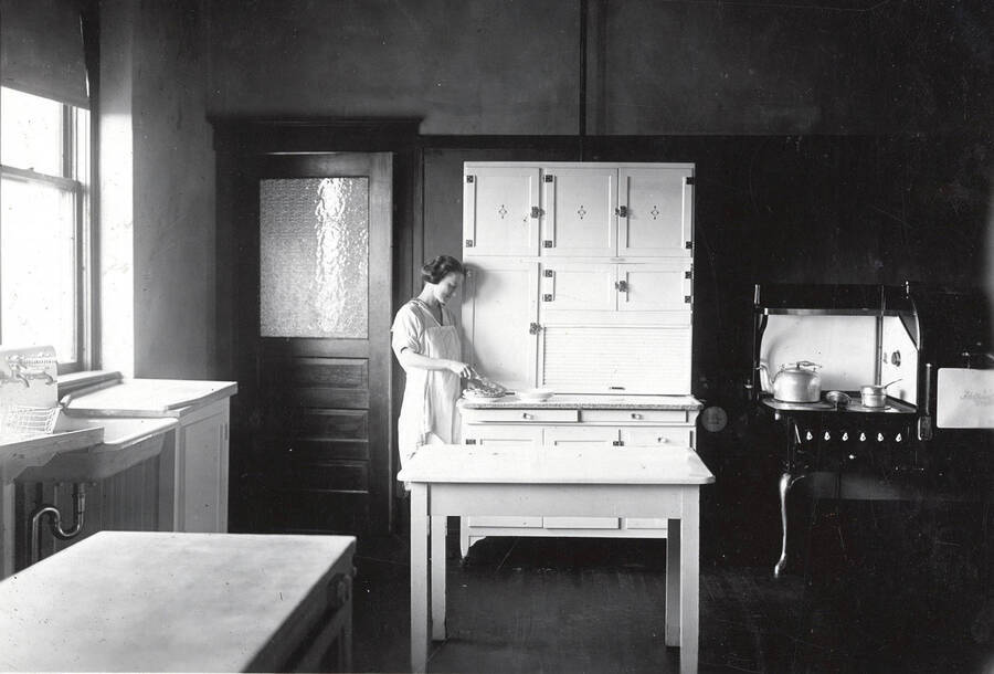 1928 photograph of Home Economics. A student in the Home Economics unit kitchen. [PG1_221-006]