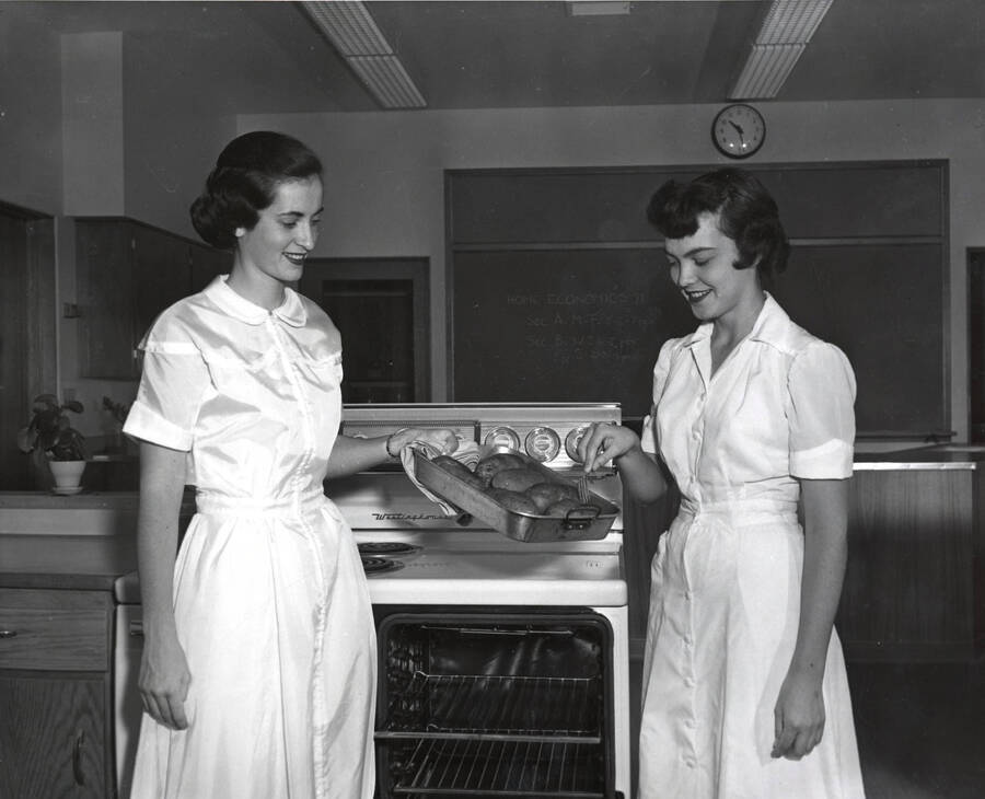 1954 photograph of Home Economics. Two students testing Idaho baked potatoes in the Home Economics kitchen. Donor: Publications Dept. [PG1_221-064]