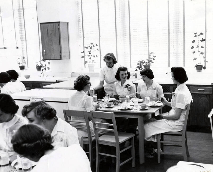 1952 photograph of Home Economics. Students eating at tables during cooking class. Donor: Publications Dept. [PG1_221-065]