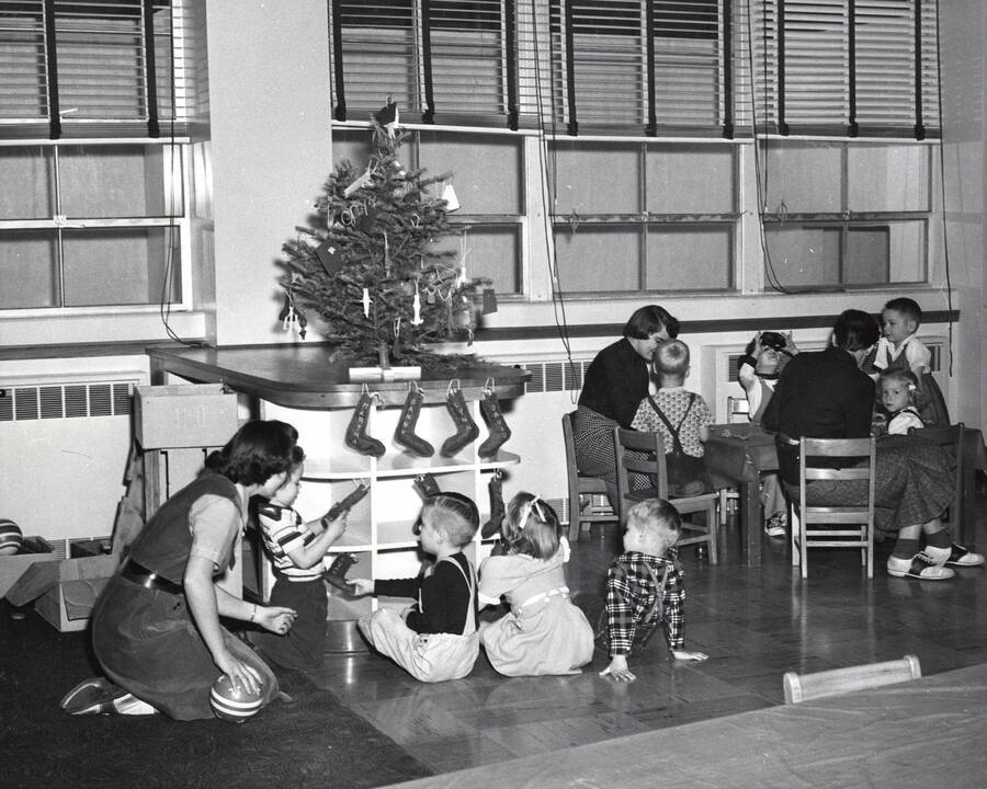 1965 photograph of Home Economics. Students with children gathered around a Christmas Tree. Donor: Publications Dept. [PG1_221-075]