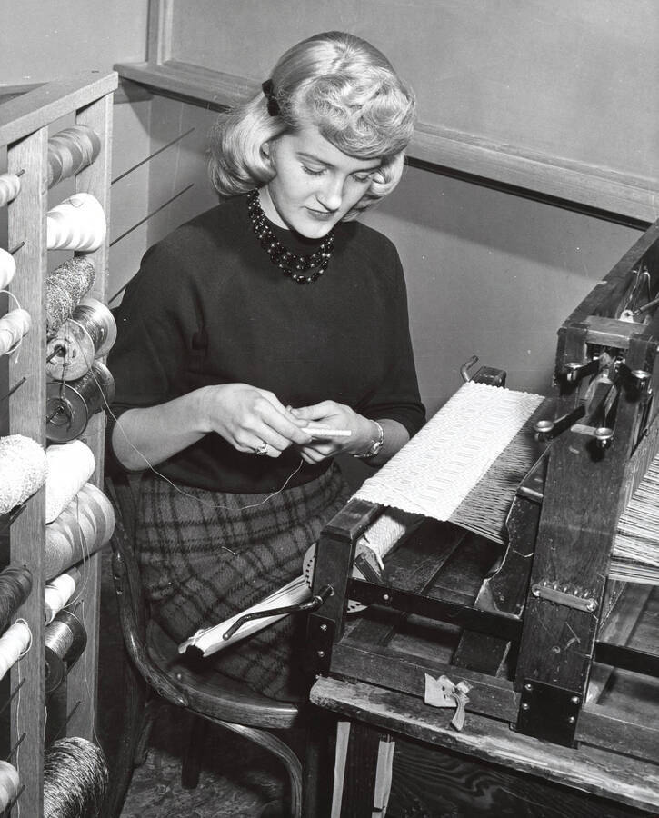 1960 photograph of Home Economics. A student threading a loom during weaving class. [PG1_221-090]