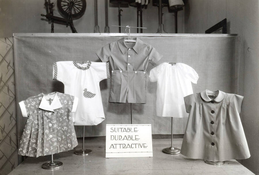 1952 photograph of Home Economics. Display of children's clothing. A sign reads 'Suitable Durable Attractive.' [PG1_221-095]