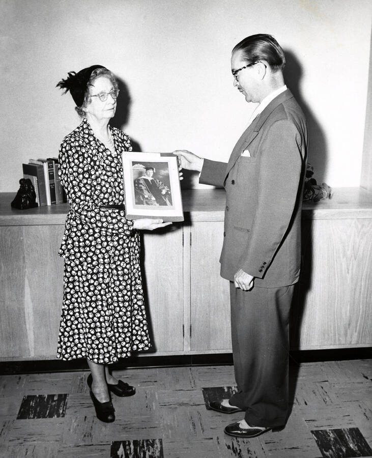 1944 photograph of Music Department. Mrs. Jay Woodworth and Hall Macklin examine a photograph. [PG1_222-012]