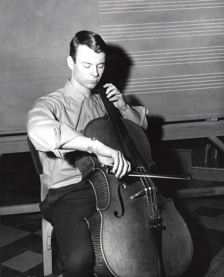 1951 photograph of Music Department. Cellist practicing in front of a blackboard. Donor: Publications Dept. [PG1_222-048]