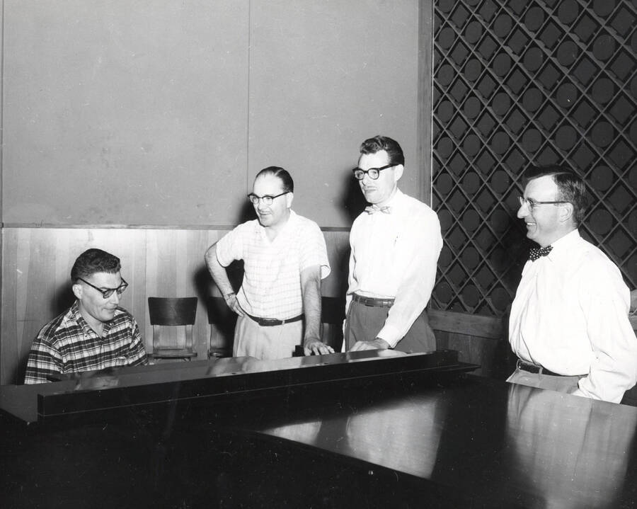 1950 photograph of Music Department. Hall Macklin, LeRoy Bauer, Glen Lockery, and an unidentified man behind a piano. Donor: Publications Dept. [PG1_222-074]