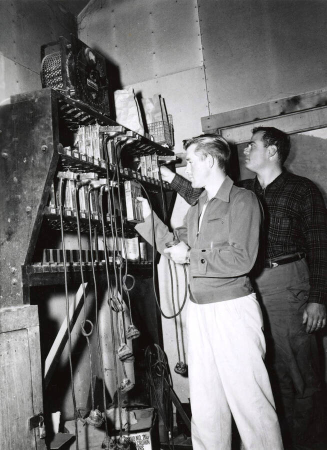 1953 photograph of College of Mines. Student examining equipment. [PG1_223-20]