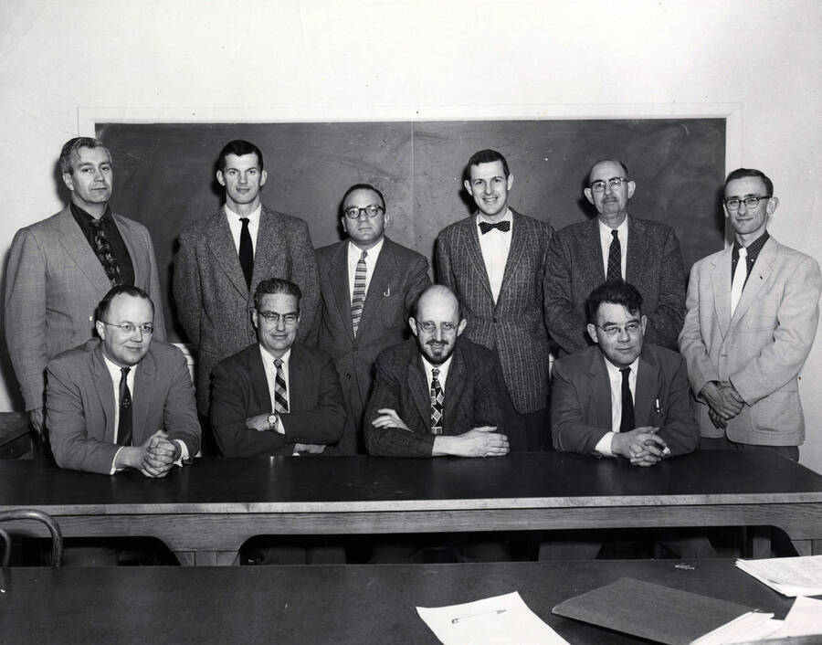 1958 photograph of College of Mines. Faculty standing in front of a blackboard. [PG1_223-23]