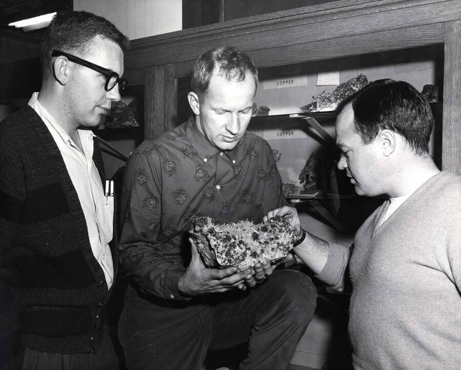 1959 photograph of College of Mines. Students examining an ore specimen. [PG1_223-05]