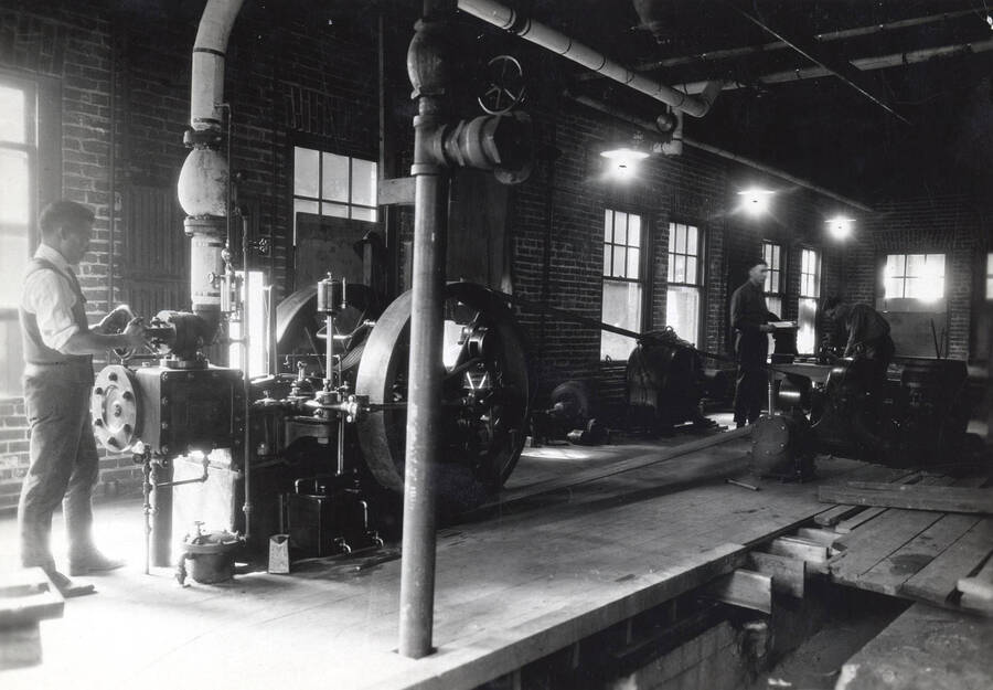 1936 photograph of College of Engineering. A student turns a valve on a steam engine. [PG1_224-13]