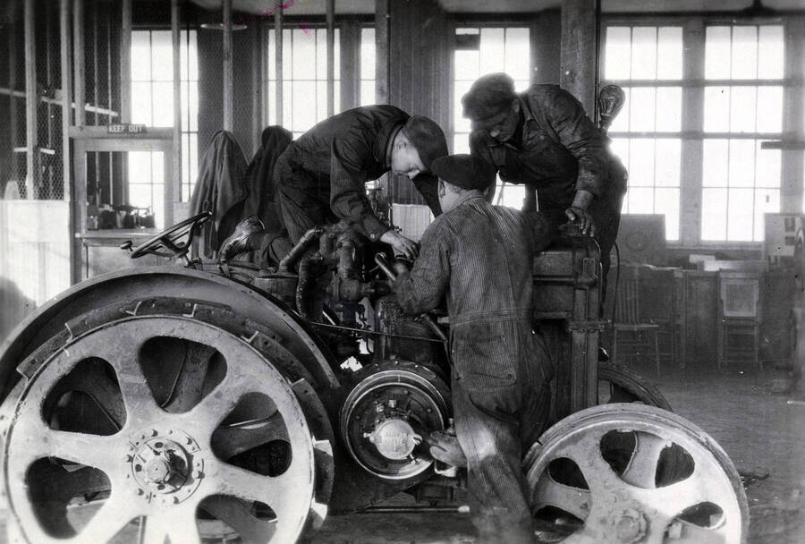 1933 photograph of College of Engineering. Students work on a tractor during class. [PG1_224-18]