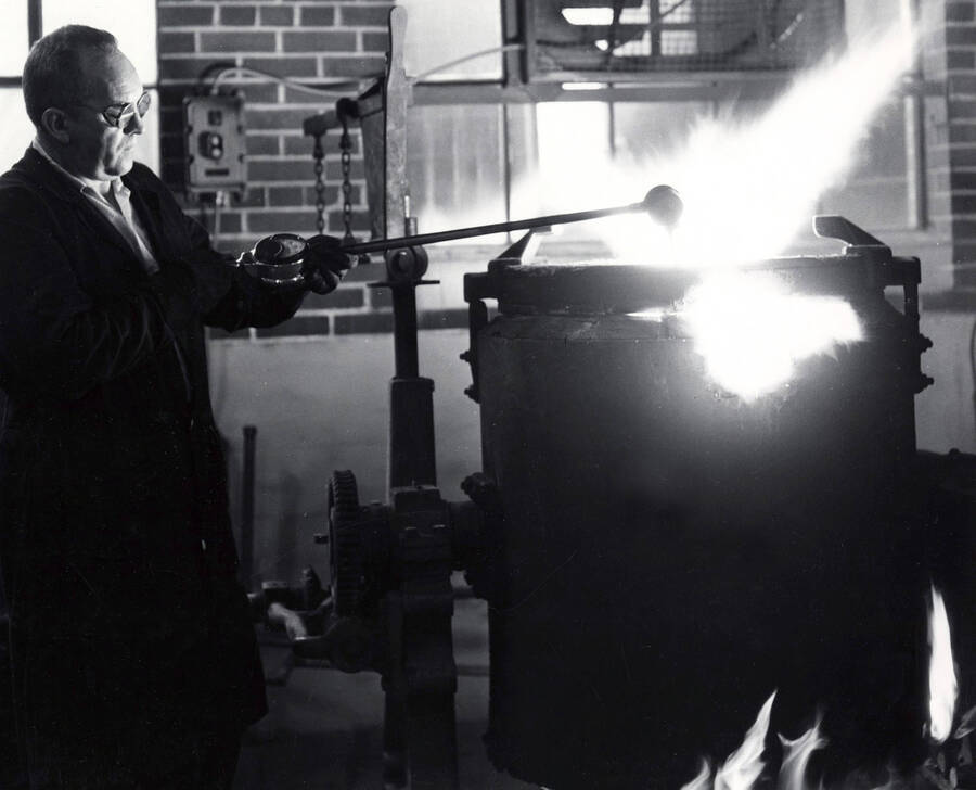 College of Engineering. University of Idaho. Wearing protective glasses, Assistant Professor Harold Amos checks the temperature of the aluminum alloy being melted for casting parts for student projects. [224-43]