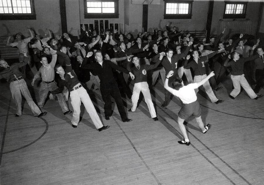 1935 photograph of Physical Education. Students dancing in the gymnasium during clog and tap-dancing class. [PG1_230-01]