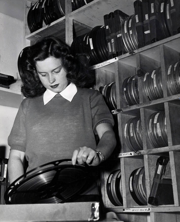 1951 photograph of Audio Visual Aids Service. A student examines a reel of film. [PG1_232-02]