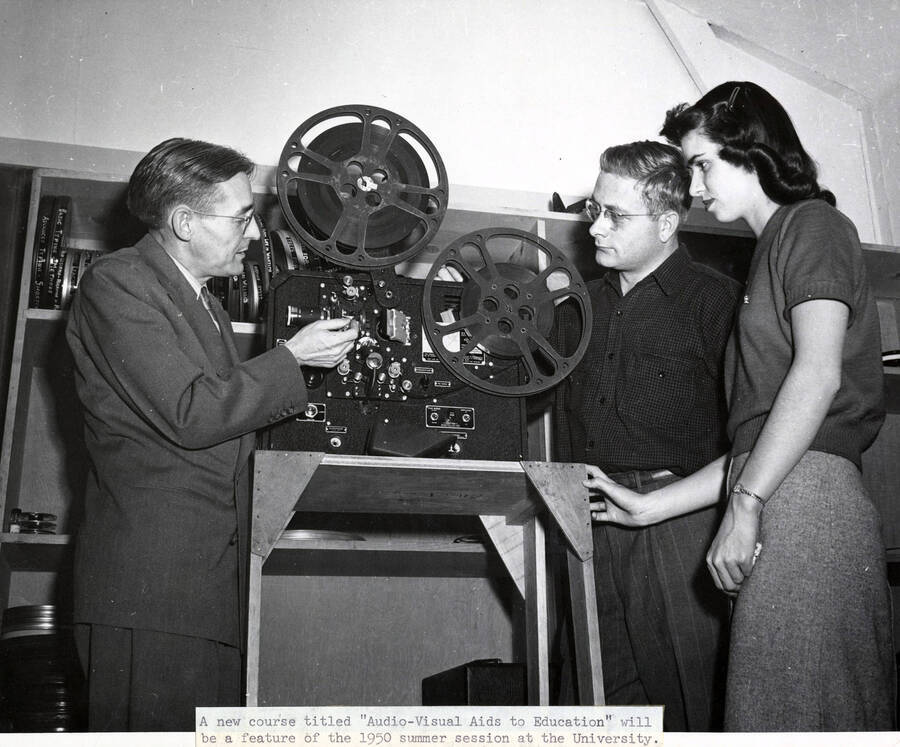 1950 photograph of Audio Visual Aids Service. Professor Allan Perry threading film in a projector. Donor: Publications Dept. [PG1_232-03]