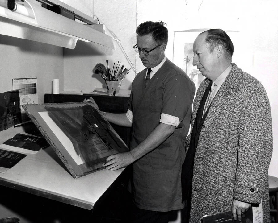 1962 photograph of Art and Architecture. Alfred Dunn showing a dust jacket to Rafe Gibbs Donor: Publications Dept. [PG1_241-12]