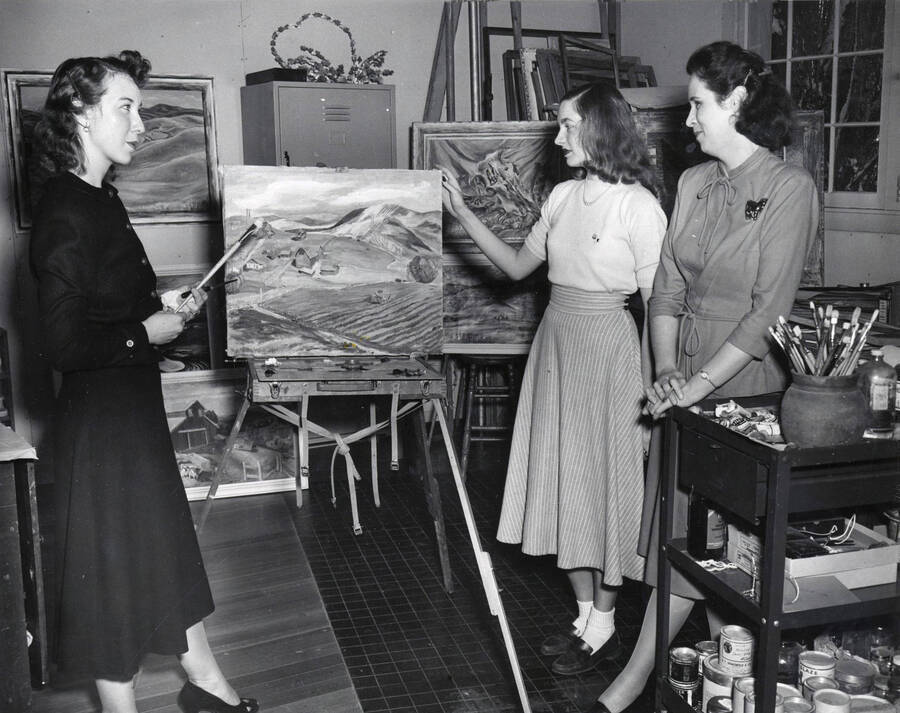 1951 photograph of Art and Architecture. Mary B. Kirkwood and two students examining paintings in a studio. Donor: Publications Dept. [PG1_241-25]