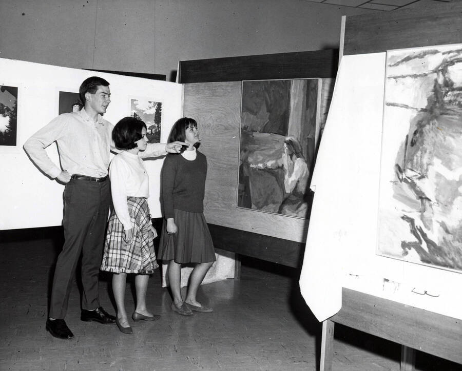 1963 photograph of Art and Architecture. Students Glenn Martz, Carol Doyle and Barbara Feil examining art during an exhibit. Donor: Publications Dept. [PG1_241-03]
