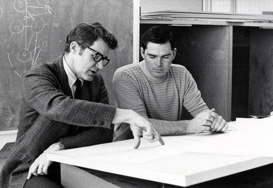 1973 photograph of Art and Architecture. Robert E. McConnell and student talking in a classroom. [PG1_241-40]