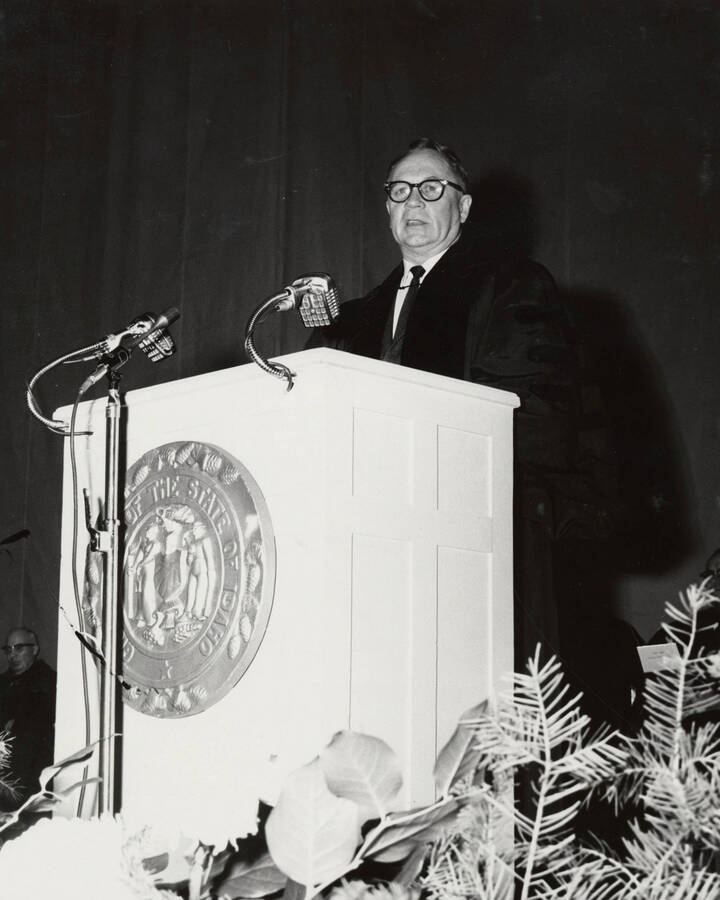 1964 photograph of 75th Anniversary. Regent Ezra M. Hawkes giving a speech at a lectern. [PG1_246-08b]