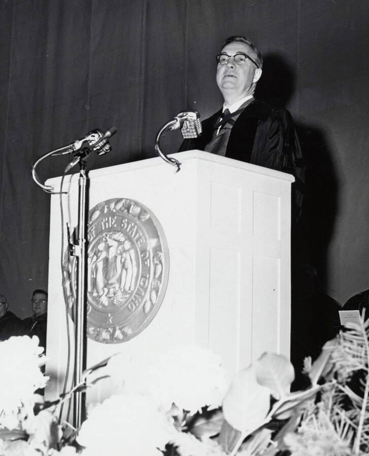 1964 photograph of 75th Anniversary. Dr. L.H. Chamberlain giving convocation address from a lectern. [PG1_246-11b]