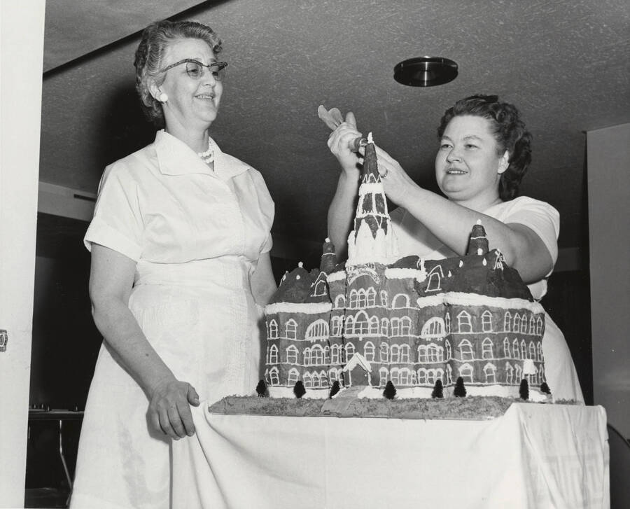 1964 photograph of 75th Anniversary. Marie Bippes and Mrs. Leroy Zeller decorate cake for the 75th Anniversary. [PG1_246-17]