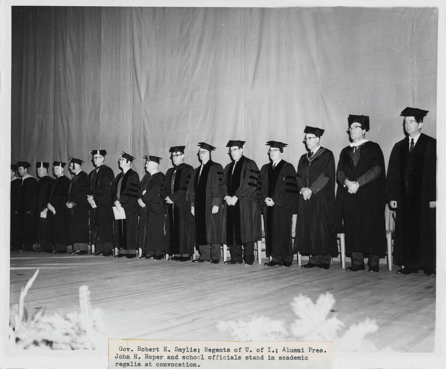 1964 photograph of 75th Anniversary. Governor Robert E. Smylie, the Regents of the U of I, Alumni President John H. Roper and other school officials in academic regalia during the convocation. [PG1_246-04]