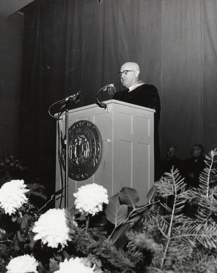 1964 photograph of 75th Anniversary. President D.R. Theophilus giving a speech from a lectern. [PG1_246-5a]