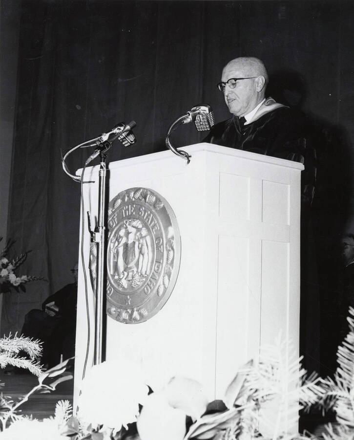 1964 photograph of 75th Anniversary. President D.R. Theophilus giving a speech from a lectern. [PG1_246-5b]