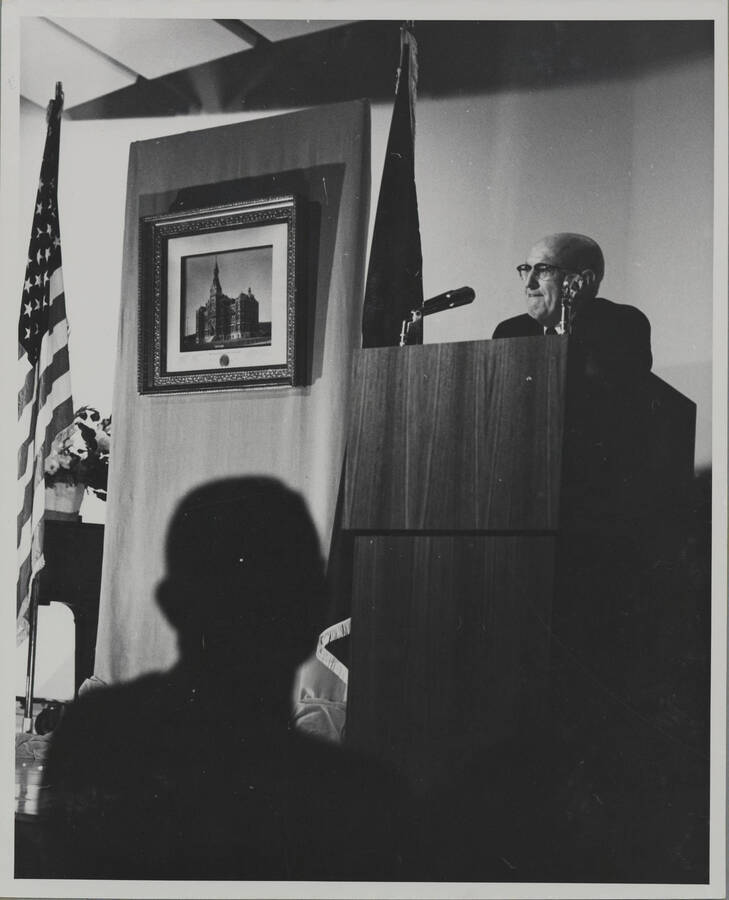 1964 photograph of 75th Anniversary. President D.R. Theophilus giving a speech from a lectern. [PG1_246-6b]