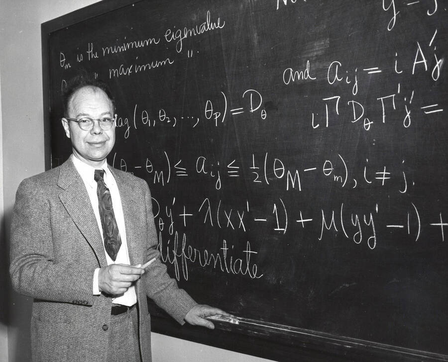 1957 photograph of Mathematics. Kenneth A. Bush in front of a blackboard. [PG1_257-01]