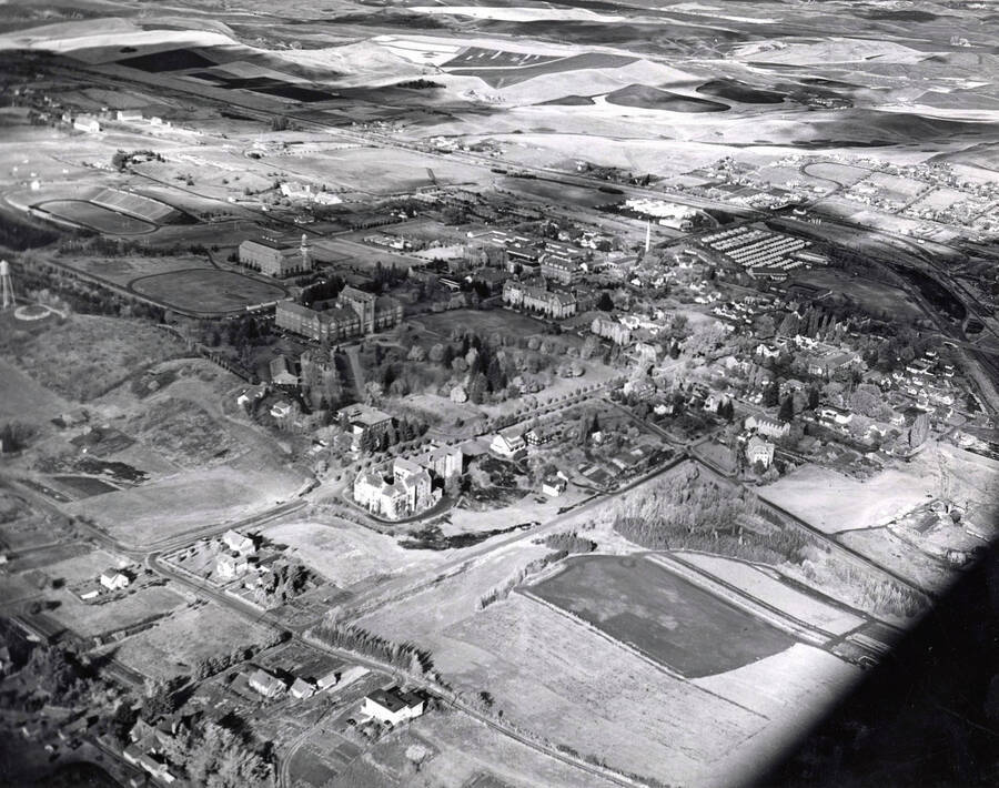 1950 photograph of University of Idaho campus. Aerial view shows both campus and the surrounding fields. Donor: Publications Dept. [PG1_003-15]